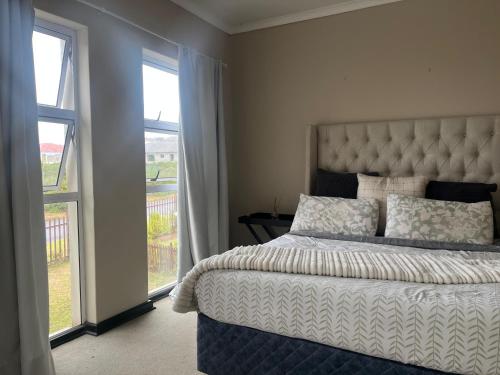 a bedroom with a bed and a large window at The Grey Ivory in Port Alfred