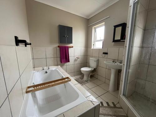 a bathroom with a tub and a toilet and a sink at The Grey Ivory in Port Alfred