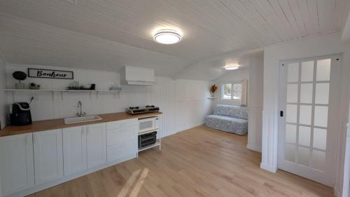 een keuken met witte kasten en een bank in een kamer bij Petit chalet au bord du lac in Shefford