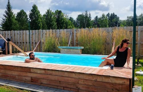 een man en een vrouw zitten in een zwembad bij Petit chalet au bord du lac in Shefford