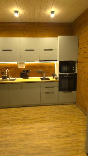 eine Küche mit weißen Schränken und einem Holzboden in der Unterkunft Спас Резорт in Spas