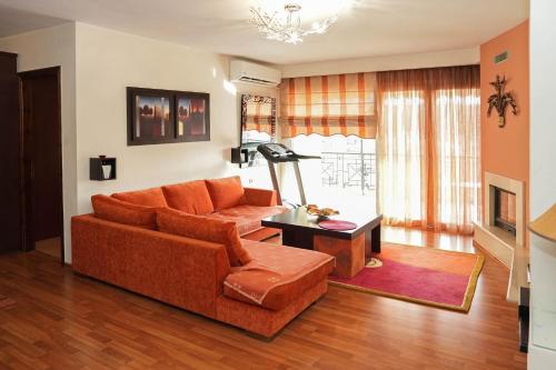 a living room with an orange couch and a table at Central Grevena Retreat with Mountain Views in Grevena