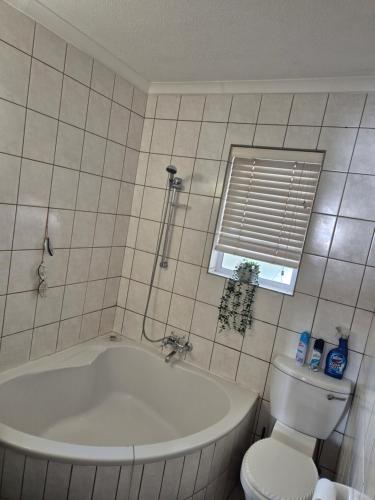 Un baño con bañera, inodoro y ventana. en langstrand apartment retreat !, en Langstrand