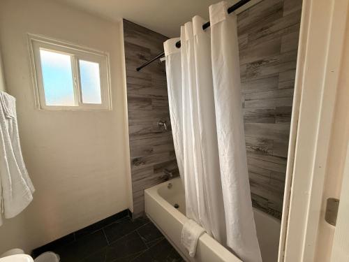 Un baño con bañera y cortina de ducha. en Del Rio Hotel O near Mesa Downtown, en Mesa