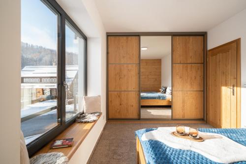 a bedroom with a bed and a large window at Aspen Lodge Apartments & Sauna in Černý Dŭl