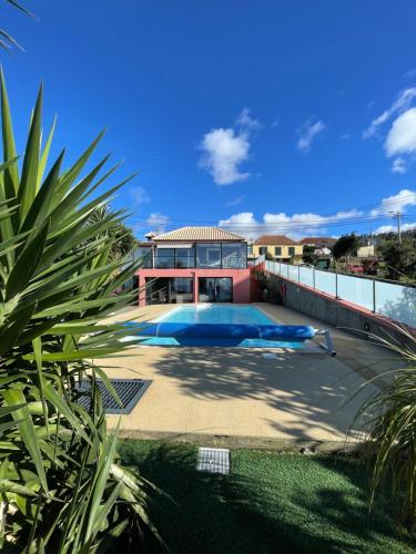 a house with a swimming pool in front of it at Sunset Paradise Villa with Heated Pool in Calheta