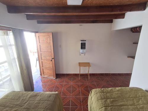 a room with two beds and a table and a door at Hostal Malú in San Pedro de Atacama