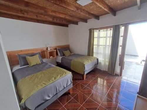 a bedroom with two beds in a room with a window at Hostal Malú in San Pedro de Atacama