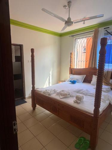 1 dormitorio con cama de madera y toallas en Jerres Inn, en Mtwapa