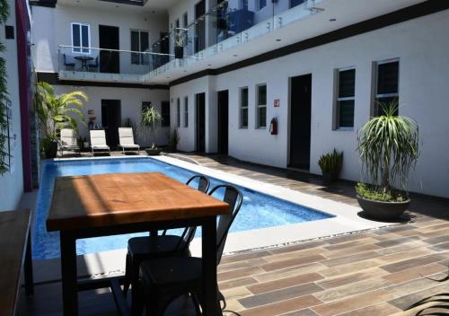 a dining table and chairs in front of a swimming pool at Hotel La Ramonna Melaque in San Patricio Melaque