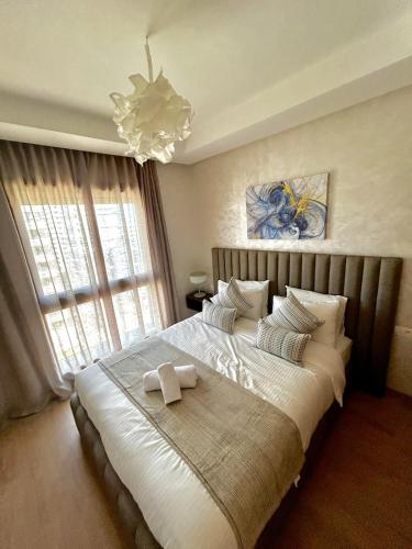 a bedroom with a large white bed with a chandelier at Luxury Studio in a secured residence in Aïn Harrouda