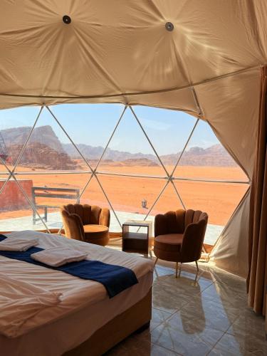a bedroom with a bed and two chairs in a tent at Ayla Rum Luxury Camp in Wadi Rum