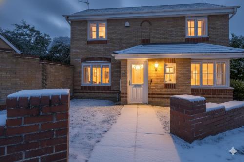 a brick house with a white door in the snow at Modern & comfy 4 bedrooms Corby house free parking in Great Oakley