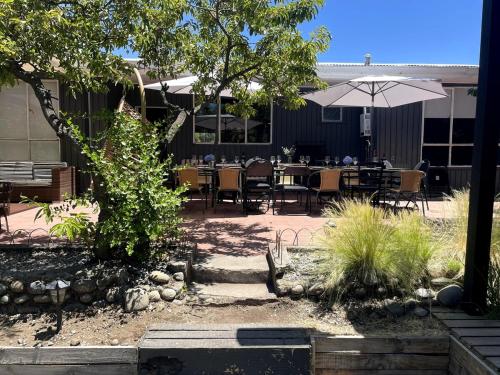 eine Terrasse mit Tischen und Stühlen und einem Sonnenschirm in der Unterkunft Agradable casa con Tina de agua Caliente y Piscina in Quillón