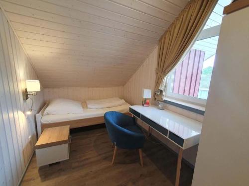 een kleine kamer met een bed en een blauwe stoel bij exklusives skandinavisches Ferienhaus in Granzow