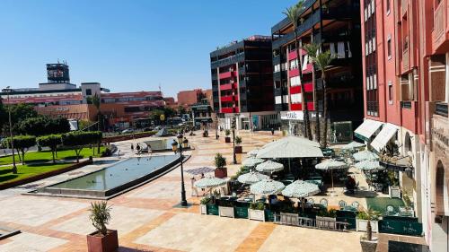 an outdoor restaurant with umbrellas and a pool in a city at Heart of Marrakech Chic & Central Gueliz Apartment - Free parking in Marrakech