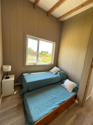 two beds in a room with a window at Cabaña Flor Tandil in Tandil