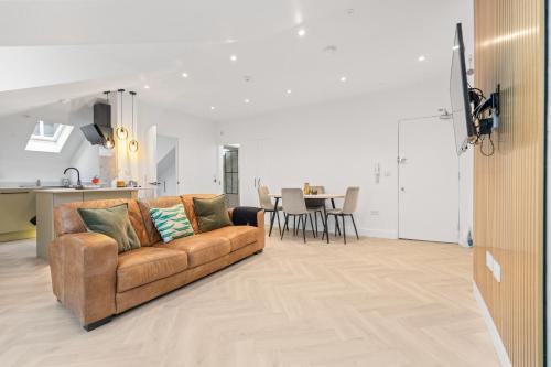 a living room with a brown couch and a kitchen at Luxury modern 1 bed between Hampstead and Camden in London