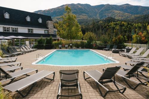 a swimming pool with lounge chairs and a resort at Gîte du Mont-Albert - Sepaq in La Martre