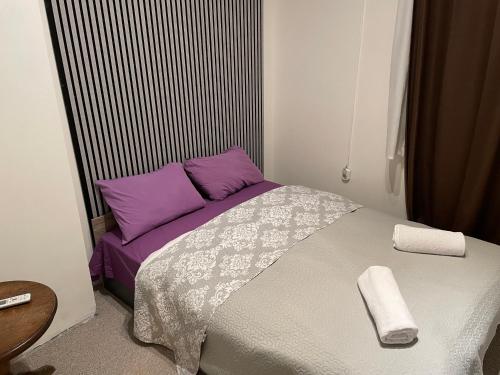 a small bedroom with a bed with purple pillows at Social Guest House in Sofia