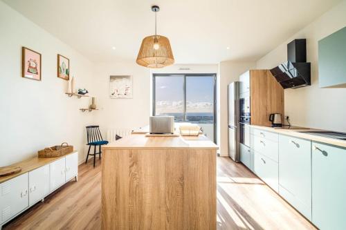 a kitchen with white cabinets and a large island with a desk at Duplex d Exception Vue sur le port de Quiberon in Quiberon