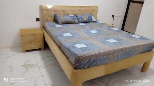 ein Bett mit Holzrahmen in einem Schlafzimmer in der Unterkunft Beuleup Résidence in Rufisque