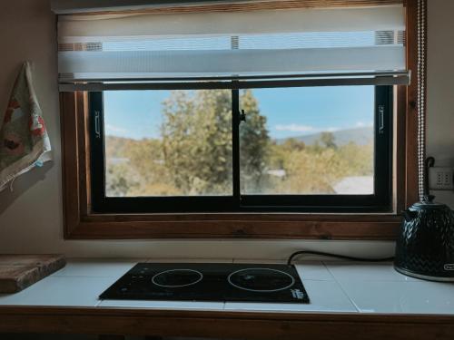 Una ventana en una cocina con estufa. en Cabaña con vista al volcán, en Neltume