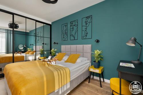 a bedroom with two beds and a blue wall at Apartments M&M, GRATIS parking, basen, sauna, siłownia in Kołobrzeg