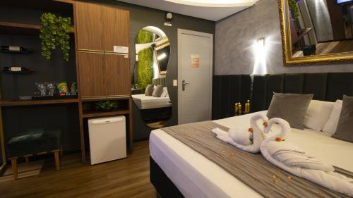 Hotel Motel Paradiso - Passo Fundo-RS في باسو فوندو: غرفة في الفندق بجعتين على سرير