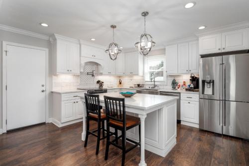 a kitchen with white cabinets and a kitchen island with chairs at Updated 2bed 2bath perfect for golfers, business travelers, and families in Greensboro