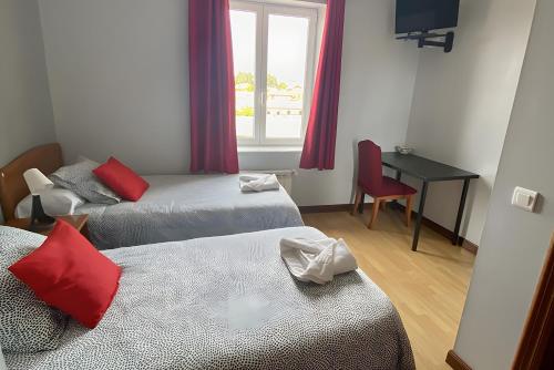 a room with two beds and a desk and a window at Hostal La Concha en Somo in Somo
