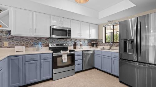 a kitchen with white cabinets and a stainless steel refrigerator at Easy Breezy - Lakefront for 6 in Sunrise Beach