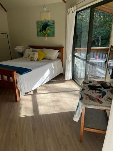 een slaapkamer met een bed en een groot raam bij Fern Cottage in Mangonui