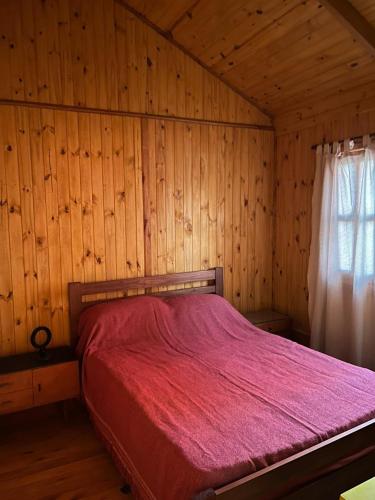 una camera con letto rosso in una camera in legno di Olivillos II a Balneario Pehuén-Có