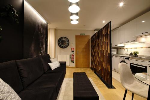 un soggiorno con un divano nero e una cucina di El Balconcillo - Boutique premium en pleno Gijón - Grupo Querbes a Gijón