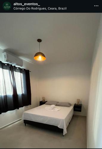 a bedroom with a white bed and a light at Da terra Altos in Aracati