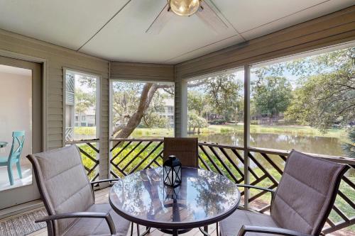 eine abgeschirmte Veranda mit einem Glastisch und Stühlen in der Unterkunft Turtle Cove 5529 in Kiawah Island