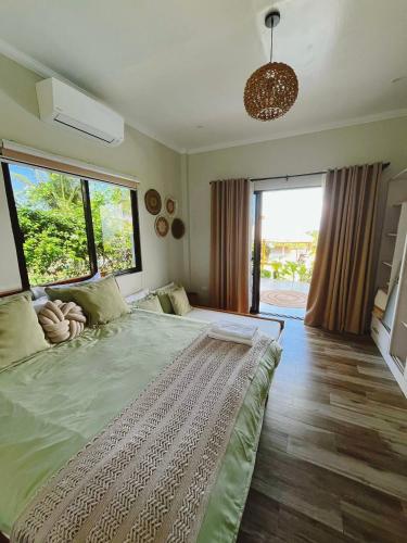 a bedroom with a large bed with a large window at Sondela Cabin Lambug 3BR exclusive Villa in Badian