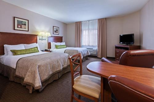 una camera d'albergo con due letti e una scrivania di Candlewood Suites - Texas City by IHG a Texas City