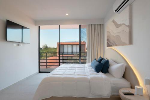 a bedroom with a white bed and a large window at The Retreat at Sisal in Sisal