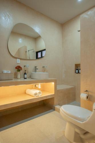 a bathroom with a sink and a toilet and a mirror at The Retreat at Sisal in Sisal