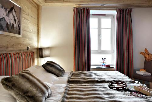a bedroom with a bed with a blanket and a window at CGH Résidences & Spas Le Jhana in Tignes