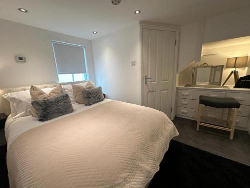 a bedroom with a white bed with a dresser and a mirror at One bed Mews House in Northwood