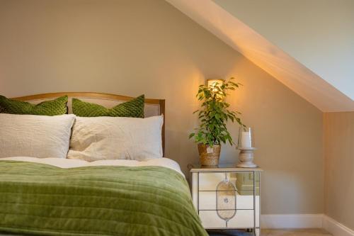 NetleyにあるHealth & Wellness House Hot Tub, Sauna & Ice Bathのベッドルーム1室(緑の毛布と植物付)