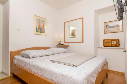 una camera da letto con un letto con lenzuola bianche e una radio di House Frane a Supetar (San Pietro di Brazza)