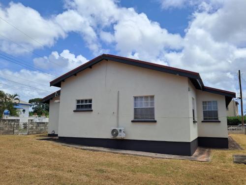 Lovely 3-bedroom house located near Oistins, close to beaches and Golf course في كرايست تشيرش: بيت أبيض بسقف أسود