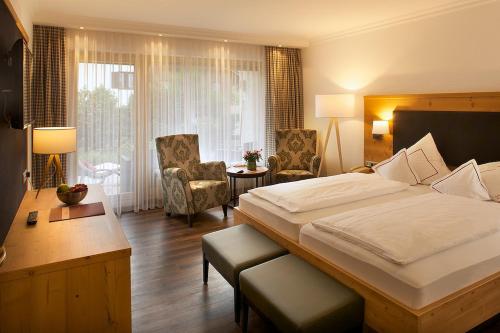 a hotel room with a bed and a desk and chairs at Hotel Menning ***S in Oberstdorf