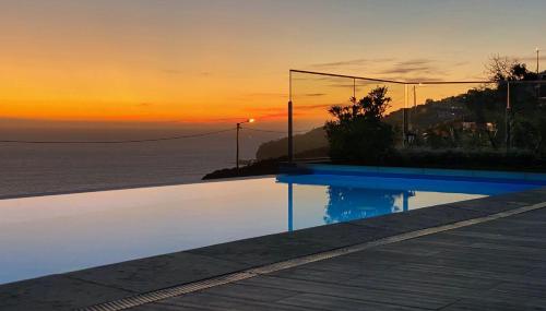 a swimming pool with a view of the ocean at sunset at Holiday Apartment Sunset Ocean in Ribeira Brava