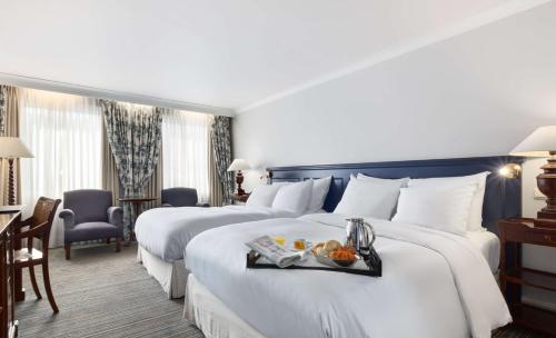 a hotel room with two beds with a tray of food on it at NH Brugge in Bruges