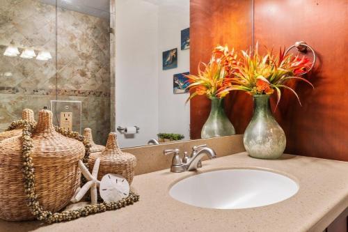 a bathroom with a sink and two vases with flowers on it at International Colony Club 23 · ICC 23 3BD Kaanapali Plantation C in Lahaina